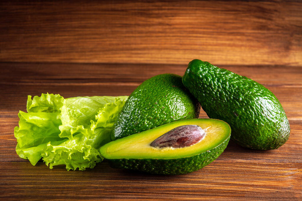 Салат и авокадо на старинном деревянном столе. Сырые фрукты здоровой зеленой пищи. Авокадо баннер или диетическая концепция - Фото, изображение