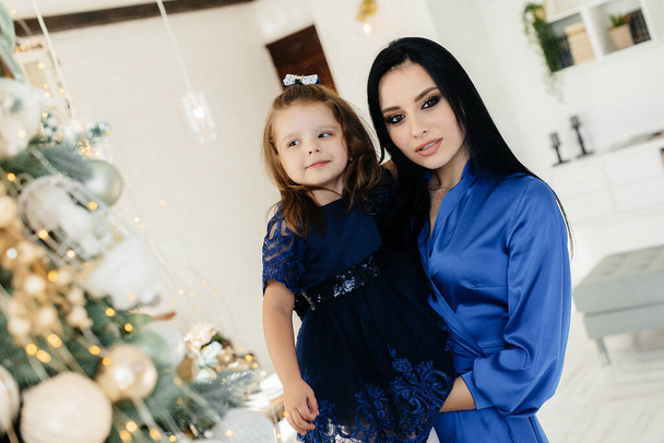 Mom and daughter celebrate and play near the Christmas tree at Christmas. Holiday. - Valokuva, kuva