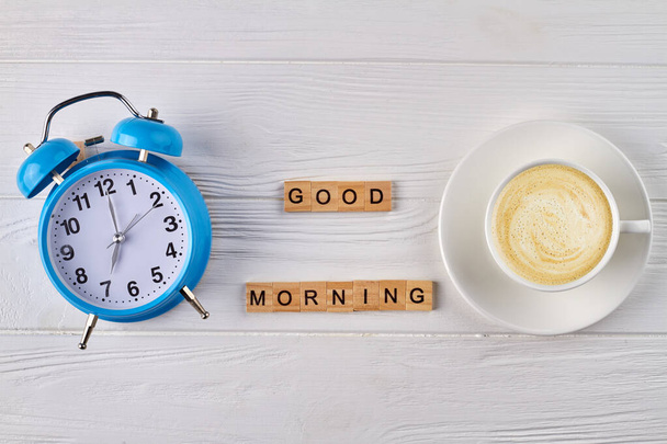 Reloj despertador con vista superior y taza de café vacía. - Foto, Imagen