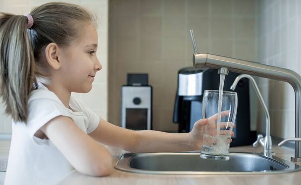 Child open water tap. Kitchen faucet. Glass of clean water. Pouring fresh drink. Hydration. Healthy lifestyle. Water quality check concept. World water monitoring day. Environmental pollution problem - Foto, imagen
