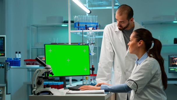 Ученые обсуждают перед компьютером с зеленым цветовым экраном - Фото, изображение