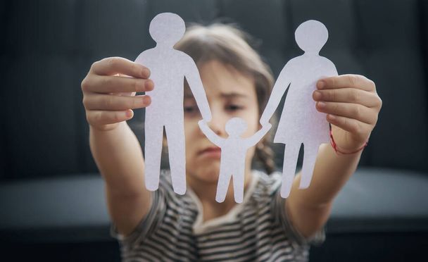 Kind met een papieren familie in zijn handen. het begrip echtscheiding, voogdij en kindermisbruik. Selectieve focus. Mensen. - Foto, afbeelding