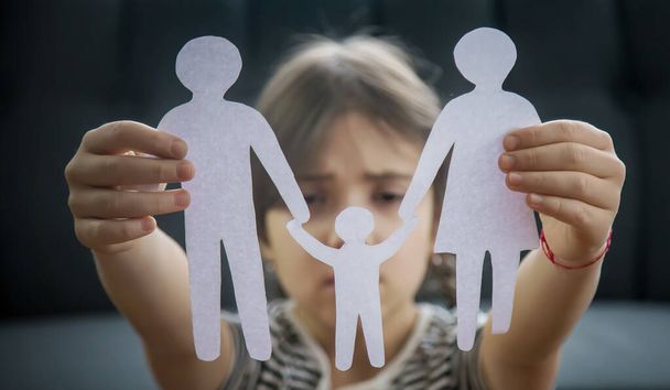 Kind mit Papierfamilie in der Hand. das Konzept von Scheidung, Sorgerecht und Kindesmissbrauch. Selektiver Fokus. Menschen. - Foto, Bild