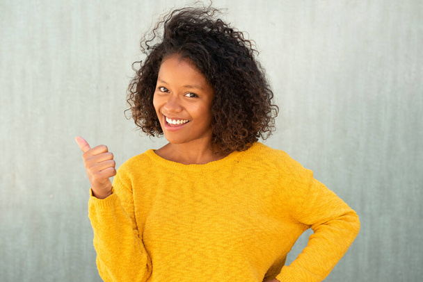 Lähikuva muotokuva kaunis nuori nainen kihara tukka hymyillen peukalot ylös käsi merkki - Valokuva, kuva