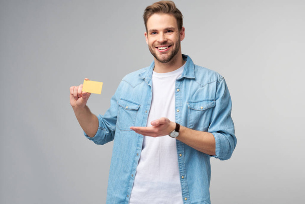 Handsome happy young man showing blank bank cor discount card - Foto, Imagen