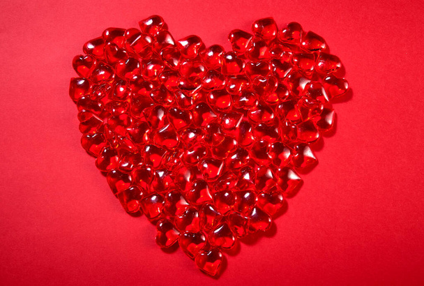 the heart is made up of sweet candies in the shape of hearts on a red paper background - Photo, Image