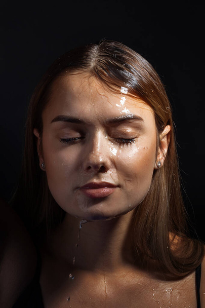 Water runs down my face. Portrait of a young beautiful woman - 写真・画像