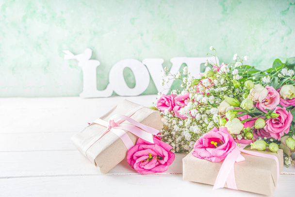 Beautiful spring flowers on white wooden background. Festive floral composition with craft paper  gift boxes. Valentine's day, Womans day, mothers day greeting card . Top view flat lay - Fotoğraf, Görsel