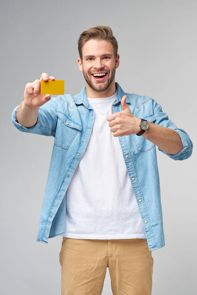 Handsome happy young man showing blank bank cor discount card - 写真・画像