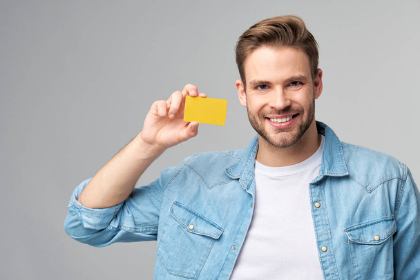 Handsome happy young man showing blank bank cor discount card - 写真・画像