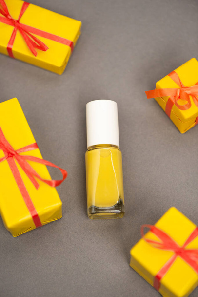 high angle view of wrapped gift boxes near bottle with yellow nail polish on grey - Photo, Image