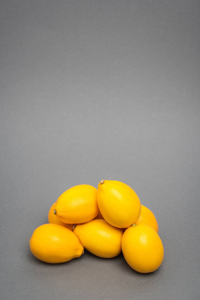 νωπά και κίτρινα λεμόνια σε γκρι φόντο - Φωτογραφία, εικόνα