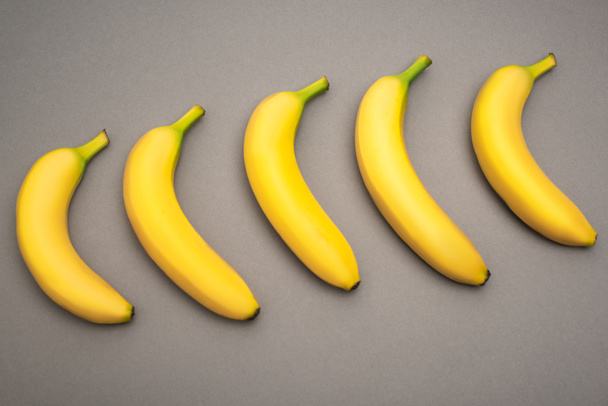 top view of yellow fresh bananas on grey background  - Foto, afbeelding