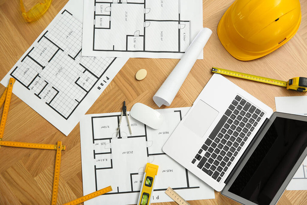 Construction drawings, laptop and tools on wooden table, flat lay - Фото, изображение