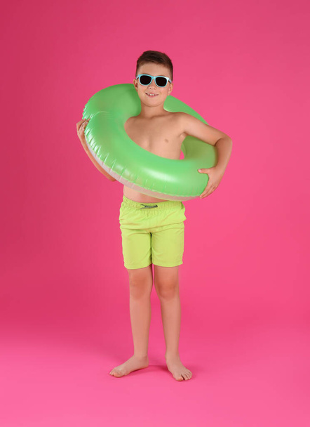 Cute little child in beachwear with bright inflatable ring on pink background - Fotó, kép