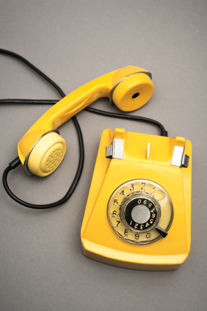 top view of retro and yellow telephone on grey background - Photo, Image