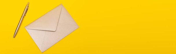 bovenaanzicht van envelop bij gouden pen geïsoleerd op geel, banner - Foto, afbeelding
