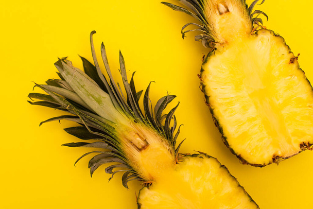 top view of halves of juicy and sweet pineapples isolated on yellow  - 写真・画像
