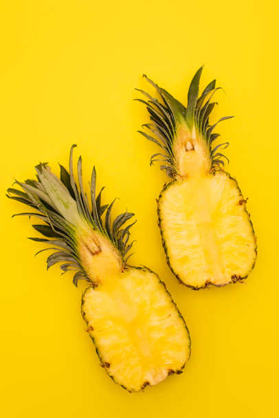 top view of halves of ripe and sweet pineapples isolated on yellow  - Foto, afbeelding