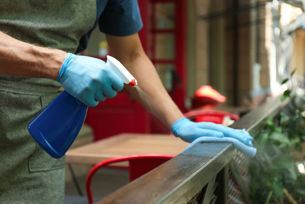 Worker in gloves disinfecting handrail outdoors, closeup - Foto, afbeelding