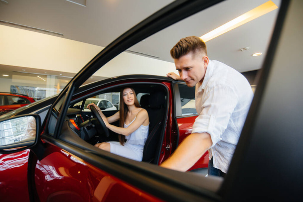 A happy young couple chooses and buys a new car at a car dealership. Buying a new car - Фото, зображення