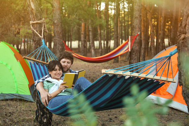 Lovely couple with book resting in comfortable hammock outdoors - Valokuva, kuva