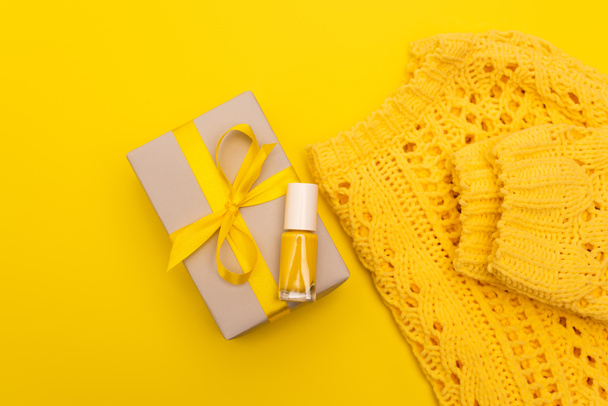 top view of nail polish on wrapped present near jumper isolated on yellow  - Photo, Image