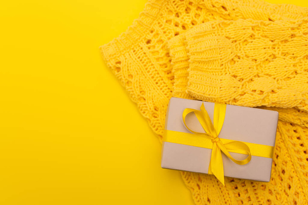 top view of wrapped present near knitted jumper isolated on yellow  - Photo, Image