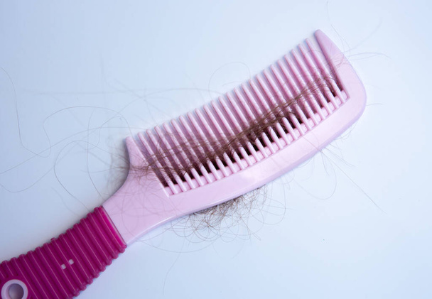 Hair loss problem. Pink comb on white background. - Photo, Image