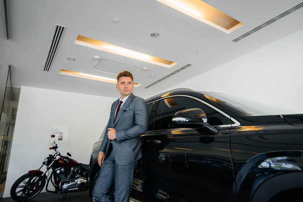 A young businessman looks at a new car in a car dealership. Buying a car - Фото, зображення
