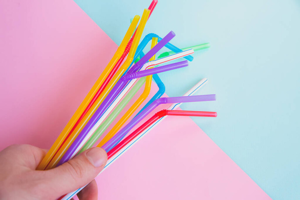 Man holding plastic straws for cocktails. Pastel pink and blue colors. Summer vibes. Hipster party with beverages. - Photo, Image