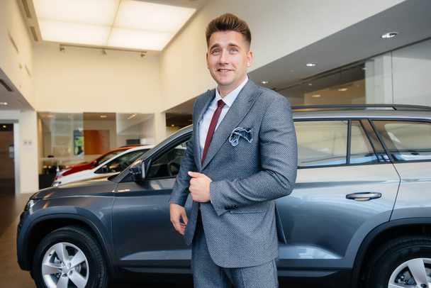 A young businessman looks at a new car in a car dealership. Buying a car - Valokuva, kuva