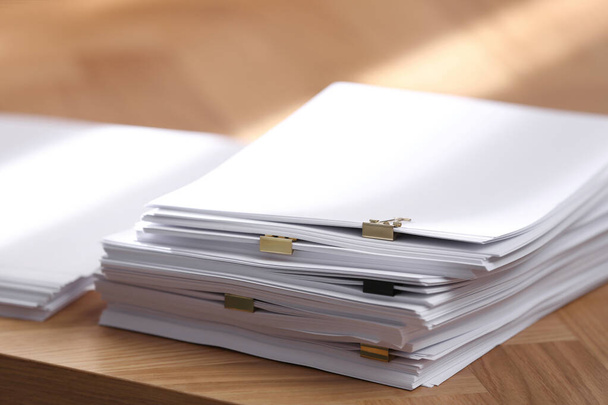 Stack of blank paper with binder clips on wooden table, closeup - Foto, immagini