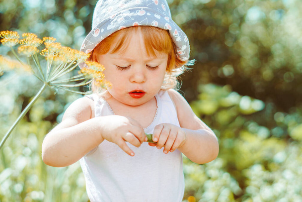 Κοριτσάκι που τρώει σταφίδες στον καλοκαιρινό κήπο - Φωτογραφία, εικόνα