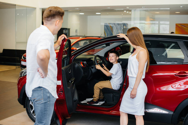 A happy young family chooses and buys a new car at a car dealership. Buying a new car - Foto, Bild
