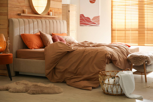 Sänky ruskea lakanat viihtyisässä makuuhuoneessa. Sisustus - Valokuva, kuva