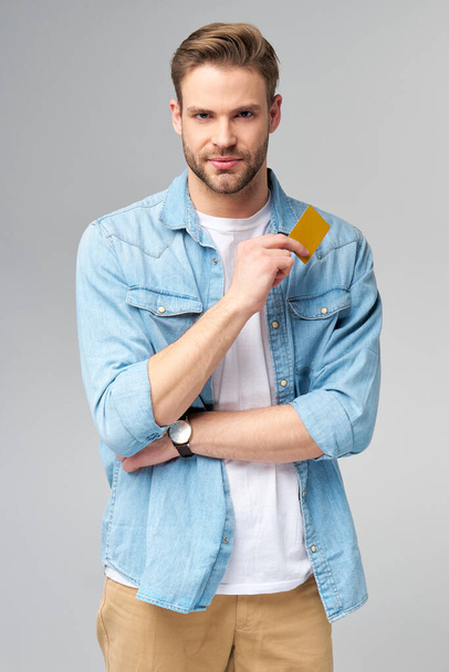 Handsome happy young man showing blank bank cor discount card - Fotoğraf, Görsel