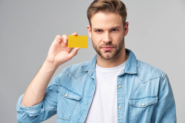 Handsome happy young man showing blank bank cor discount card - Fotoğraf, Görsel