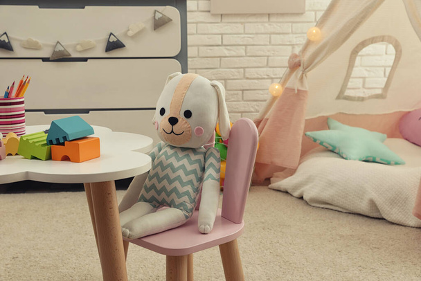 Cute toy bunny on small chair in playroom. Interior design - Фото, зображення