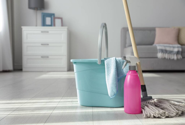 Bucket, mop and bottle of cleaning product on floor indoors. Space for text - Fotó, kép