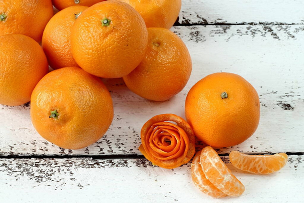 Tangerines whole, slices on a light wooden background, close-up. - Photo, Image