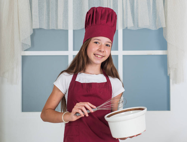 An amazing experience. kid cooking food in kitchen. choosing a career. little helper use beater. culinary and cuisine. happy childhood. happy child wear cook uniform. chef girl in hat and apron - Zdjęcie, obraz