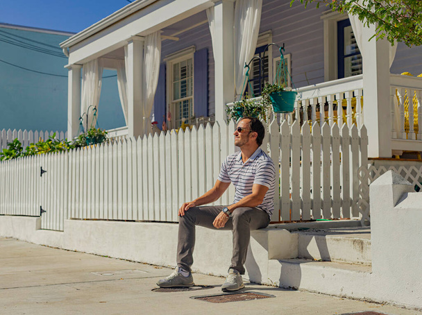 Jovem homem bonito senta-se na frente da casa - Foto, Imagem