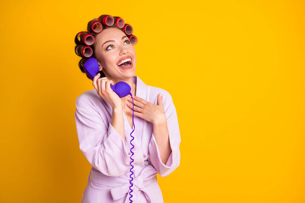 Portrait of nice glamorous cheerful woman wearing curlers talking on phone friend isolated bright yellow color background - 写真・画像