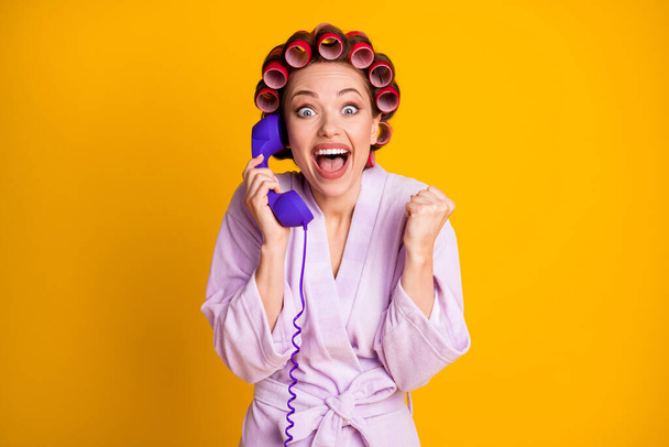 Portrait of attractive cheerful ecstatic woman wearing curlers talking on phone having fun isolated vivid yellow color background - 写真・画像