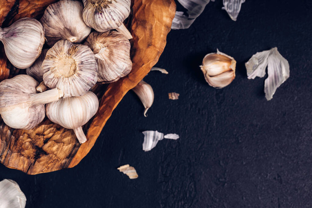 Garlic cloves and bulb in vintage wooden bowl. Lots of garlic in a bowl.  - Fotografie, Obrázek
