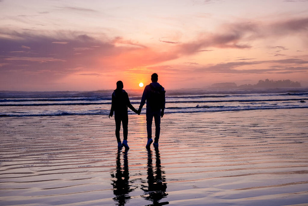 couple hommes et femmes d'âge moyen regardant coucher de soleil sur la plage de Tofino Vancouver Island Canada, magnifique coucher de soleil sur la plage avec des couleurs violettes roses dans le ciel - Photo, image