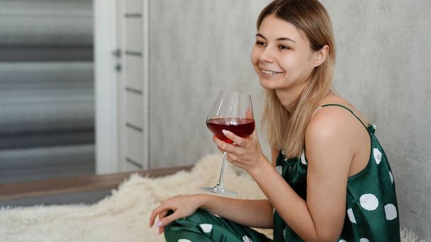 Girl in green pajamas in bed with a glass of red wine - Foto, imagen