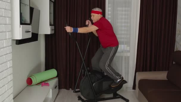 Egészséges idős idős nagypapa modell gyakorló sport edzés orbitrek szobában otthon - Felvétel, videó