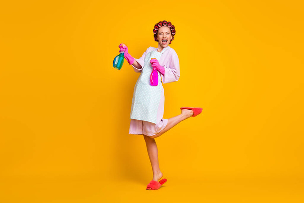 Full length body size view of pretty cheerful overjoyed maid jumping using sanitizer isolated on bright yellow color background - Фото, зображення